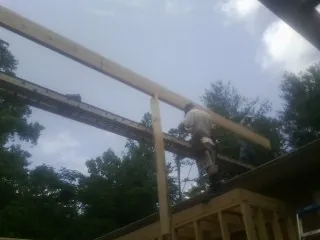 Carpenter setting a ridge beam over a new addition frame — Ice Dam Removal by Roofing Brothers in Hickory Flat