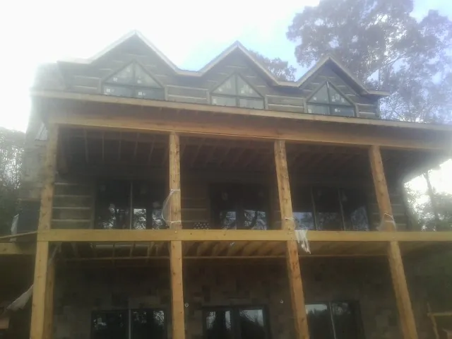 Dormers and porch framing on a large log home under construction — Roof Coating work by our crew in Hickory Flat