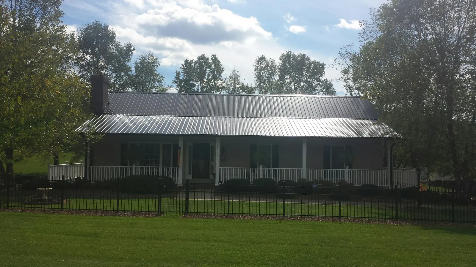 Gray metal roof on a brick ranch with a full width front porch — Gutter Guard Installation work by our crew in Hickory Flat